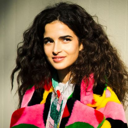 clarins double serum - woman with beautiful curly hair wearing a bright top smiling - gettyimages 1202949092