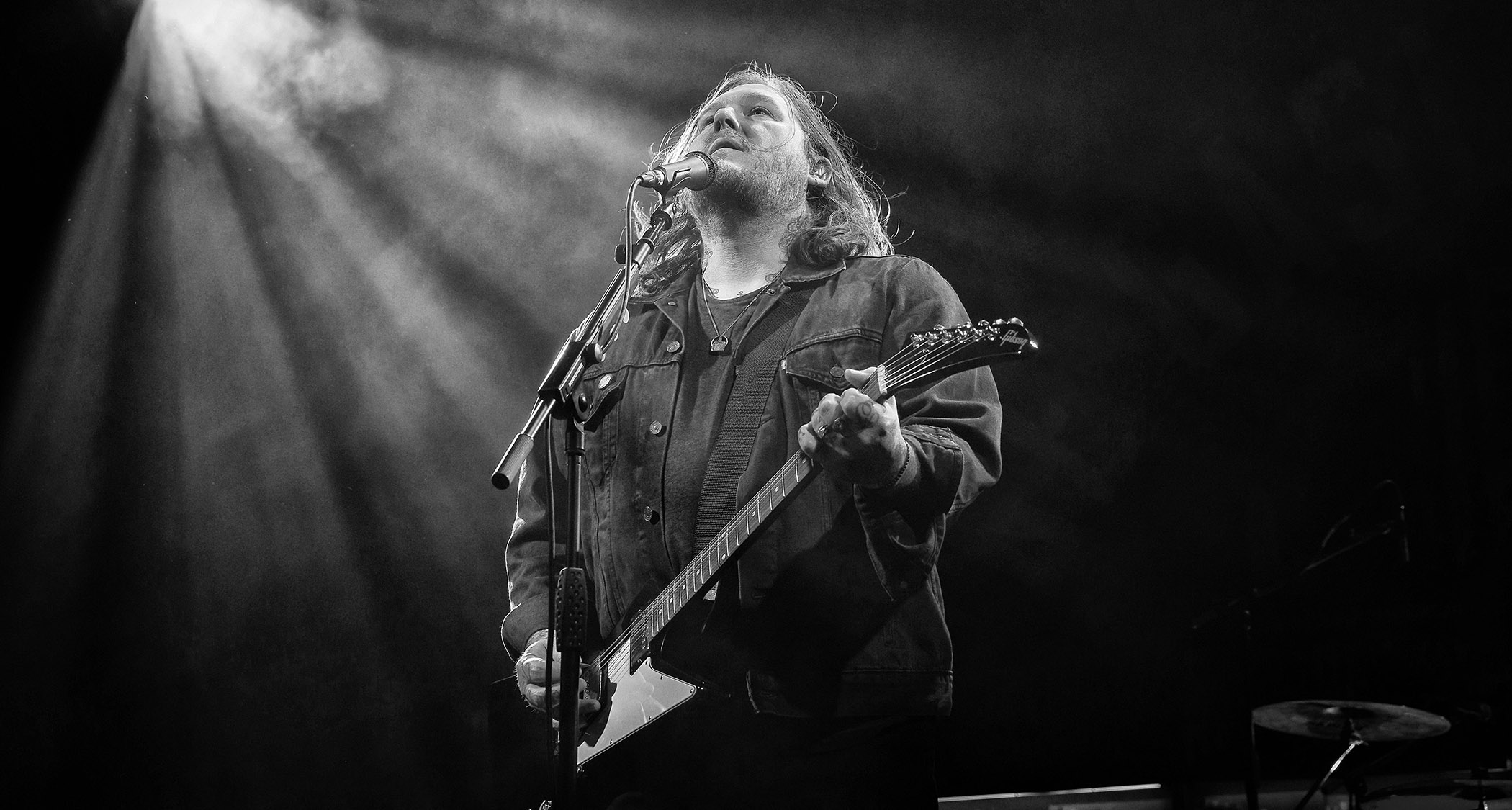 A black-and-white shot of Brian Fallon playing a Gibson Explorer onstage.