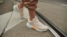 A woman crossing the street wearing Nike sneakers.