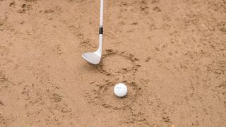 A golf club and a golf ball in a bunker at West Hill