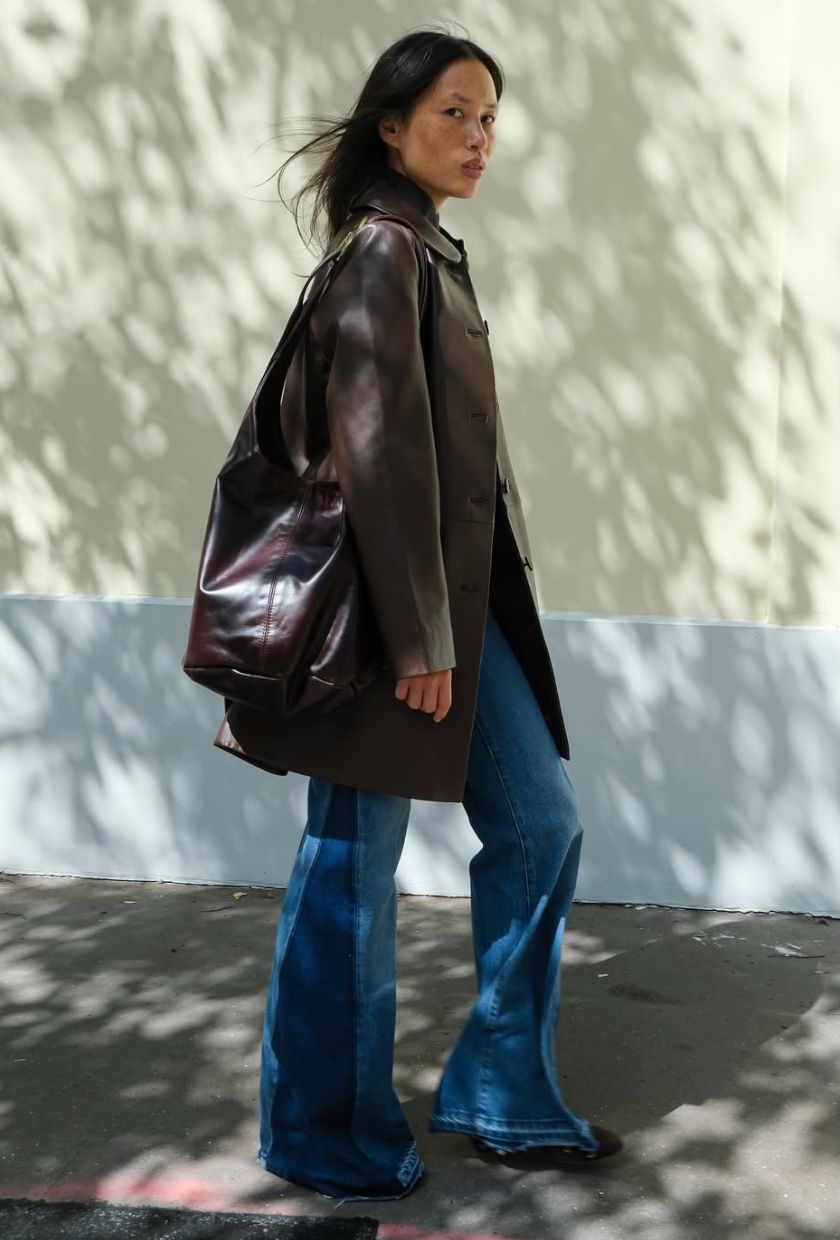 @vikilefevre wears a brown leather coat, bootcut jeans and a brown leather bag