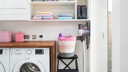 White utility room with dark wood worktop above a white washing machine