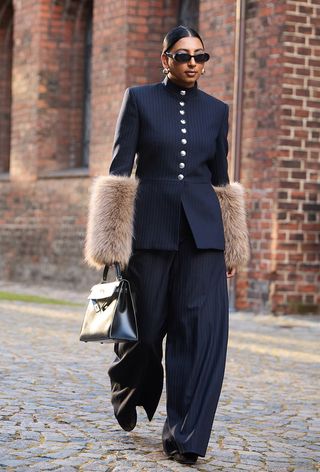 a street style photo of a woman carrying an Hermés bag in a story about how to buy an hermés bag