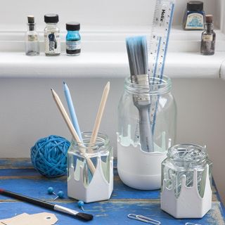 glass jars with paint brush on blue table