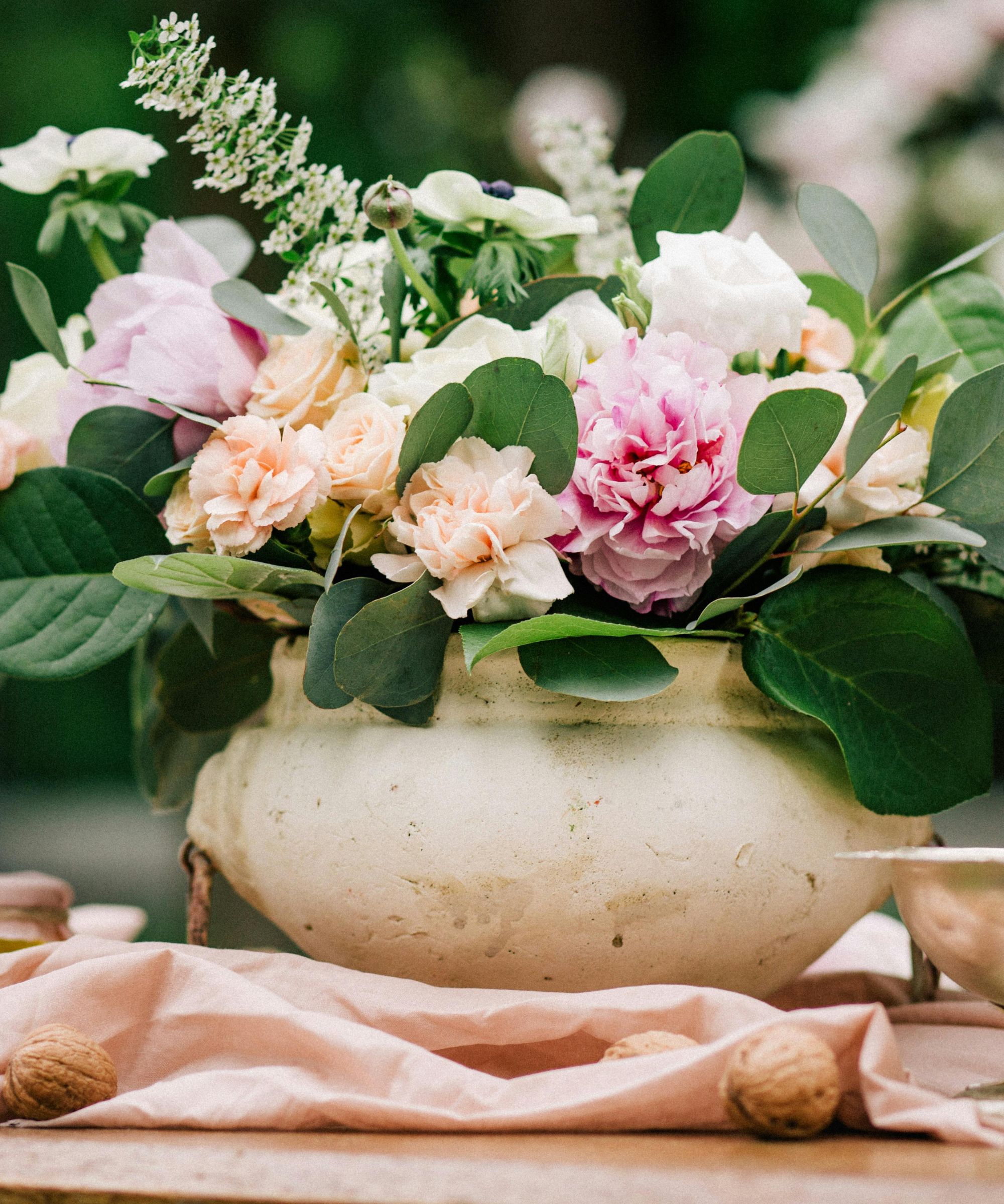 Peobies and greenery in a stone planter in an outdoor setting
