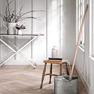 white wall room with wooden floor wooden table steel container and brush