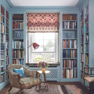 snug with blue walls filled with fitted bookcases a cosy armchair and red and white roman blind over the window kate guiness