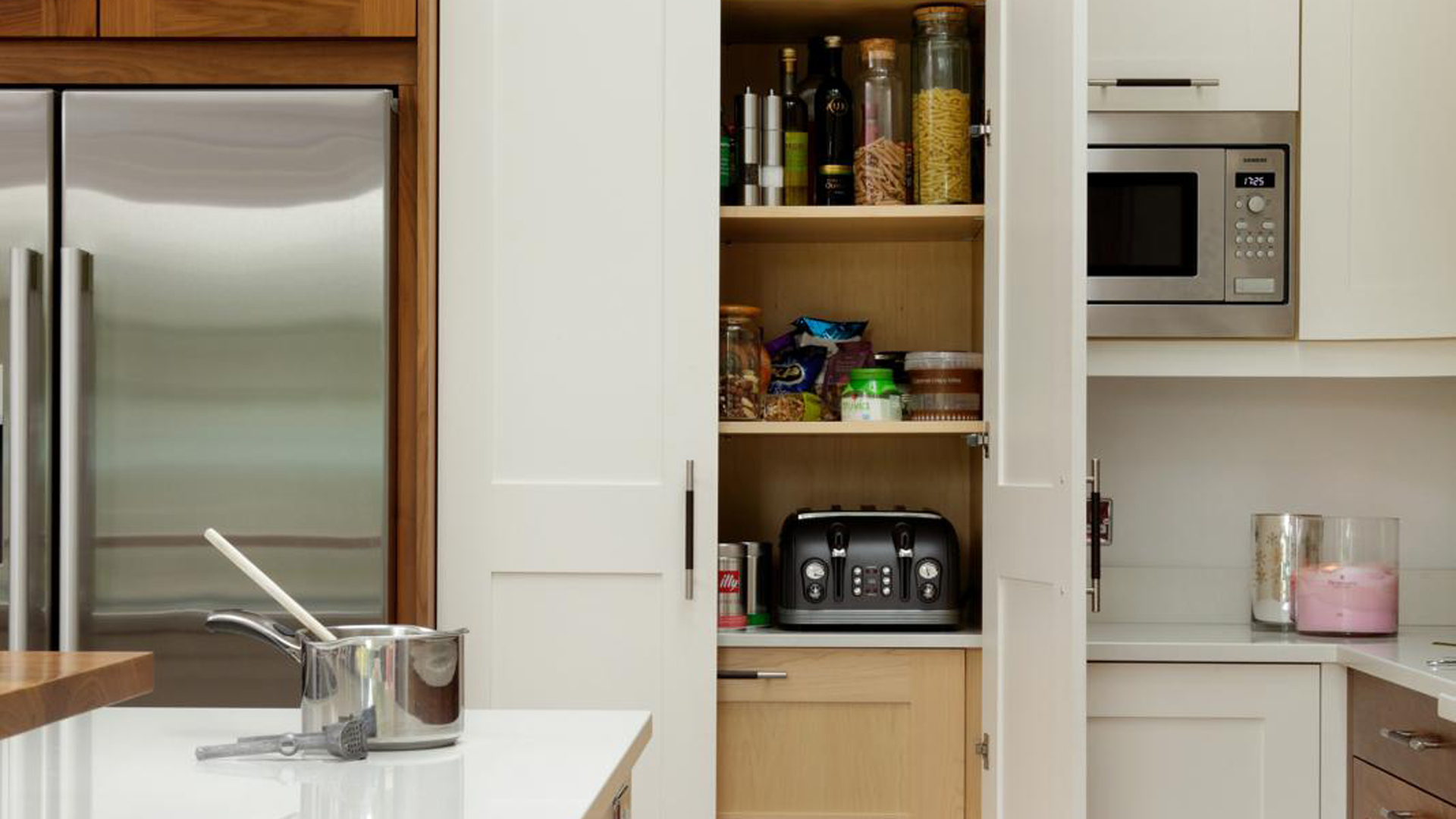White kitchen with organized pantry positioned beside the fridge and in front of the hob