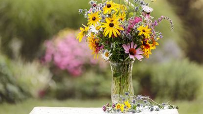 How to keep flowers fresh: Bouquet of wild flowers in vase in a garden.
