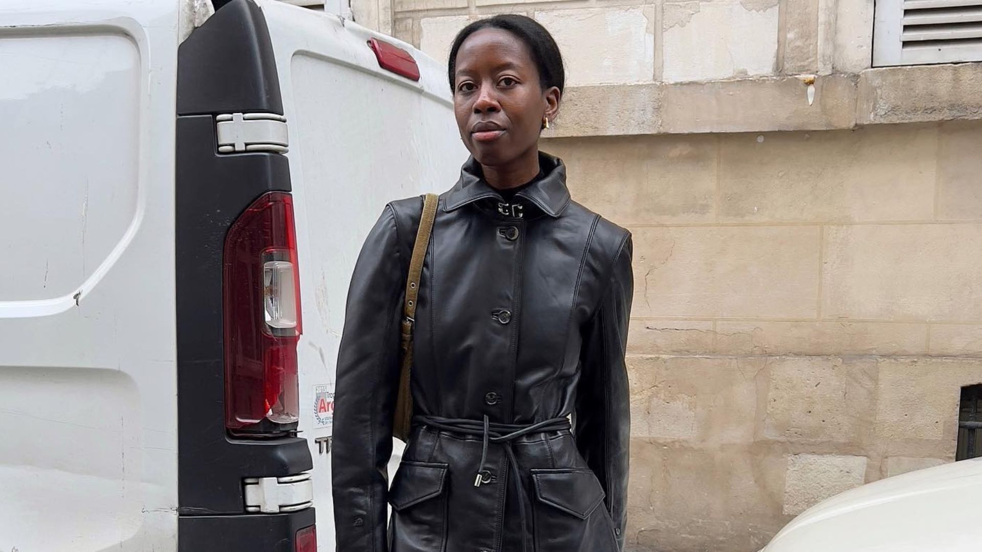 Influencer @sylviemus_ wears grey tights with peep-toe shoes and a black leather trench coat.