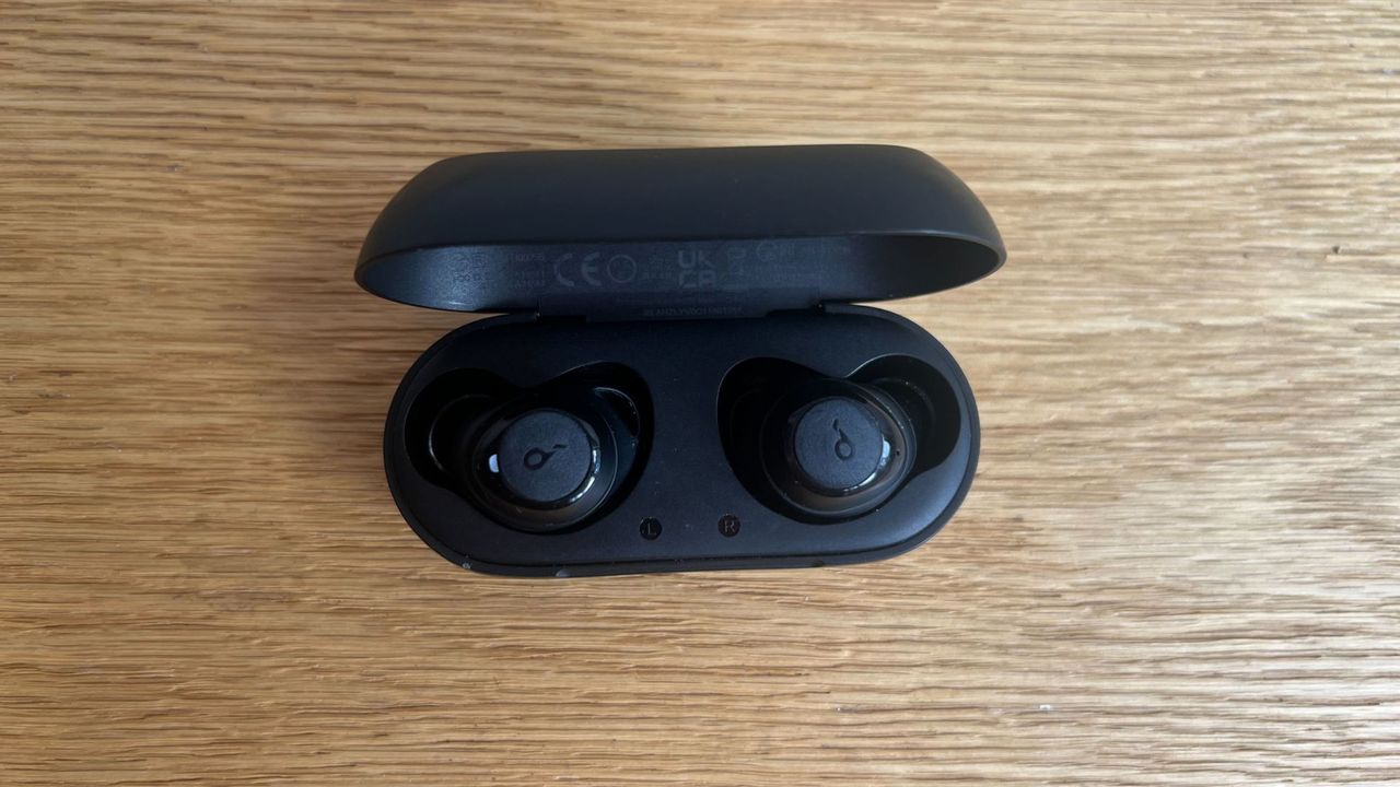 Grace Walsh testing soundcore earbuds, headphones sitting on wooden floor