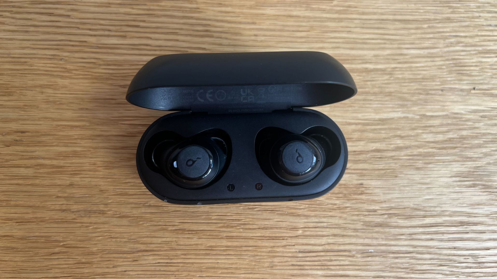 Grace Walsh testing soundcore earbuds, headphones sitting on wooden floor