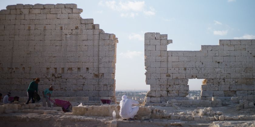 Archaeologists excavate a site with a tall wall in Egypt.
