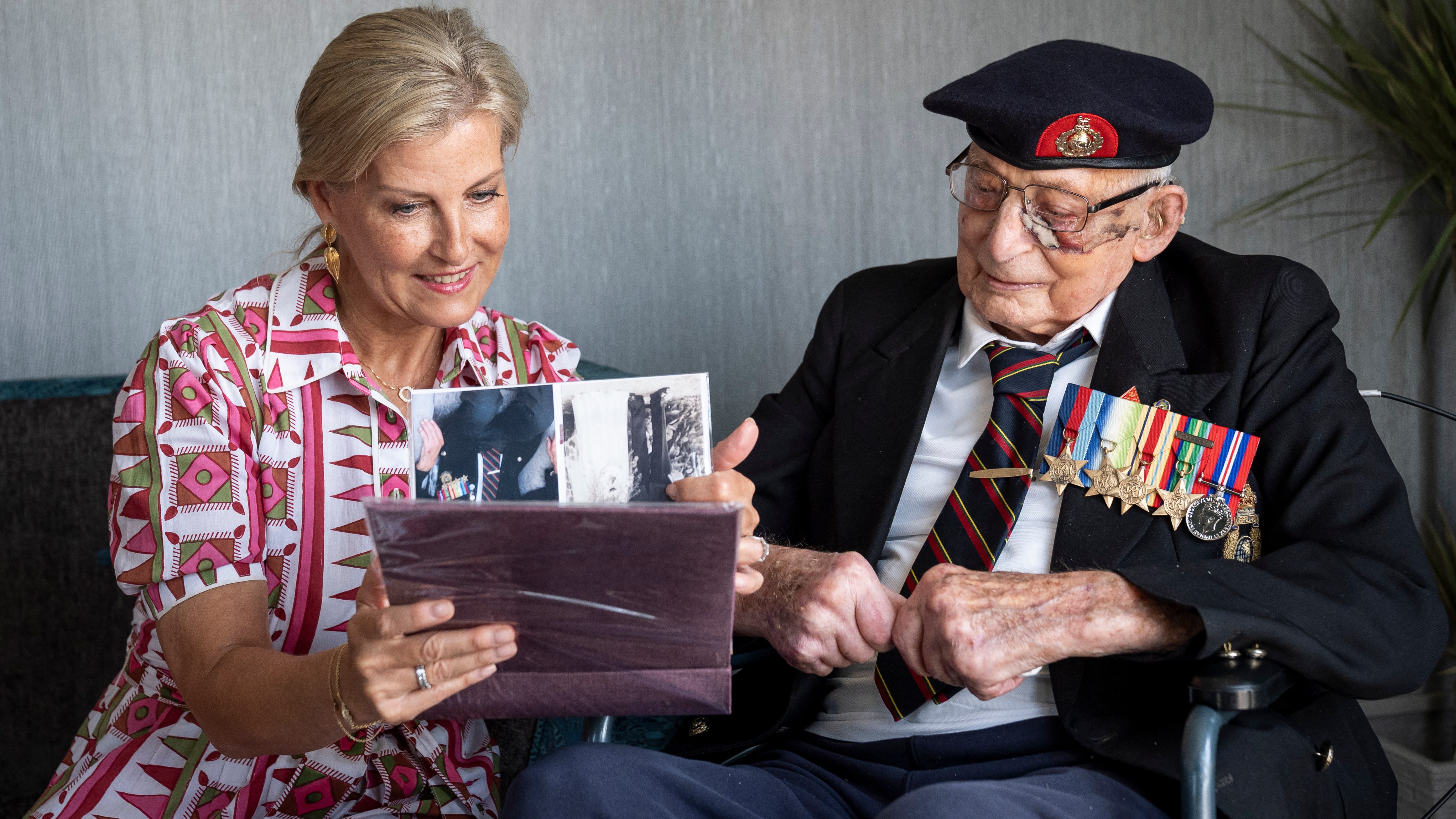 Sophie, Duchess of Edinburgh (L) looks at photographs with 105-year-old Royal Marines veteran James 'Jim' Wren (R) at the Old Sarum Manor Care Home in Salisbury on August 12, 2025
