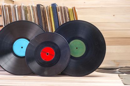 Vinyl record in front of a collection of albums, vintage process.