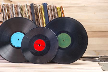 Vinyl record in front of a collection of albums, vintage process.