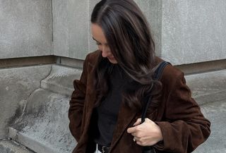 Liv Perez wearing a brown suede Madewell x Alexa Chung trench coat with a black shirt and white jeans.