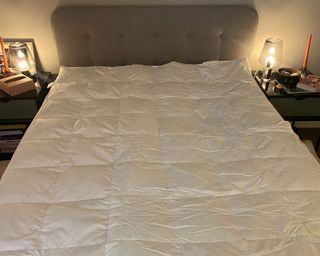 DUSK supreme goose down mattress topper on the bed with lights on and light grey headborard