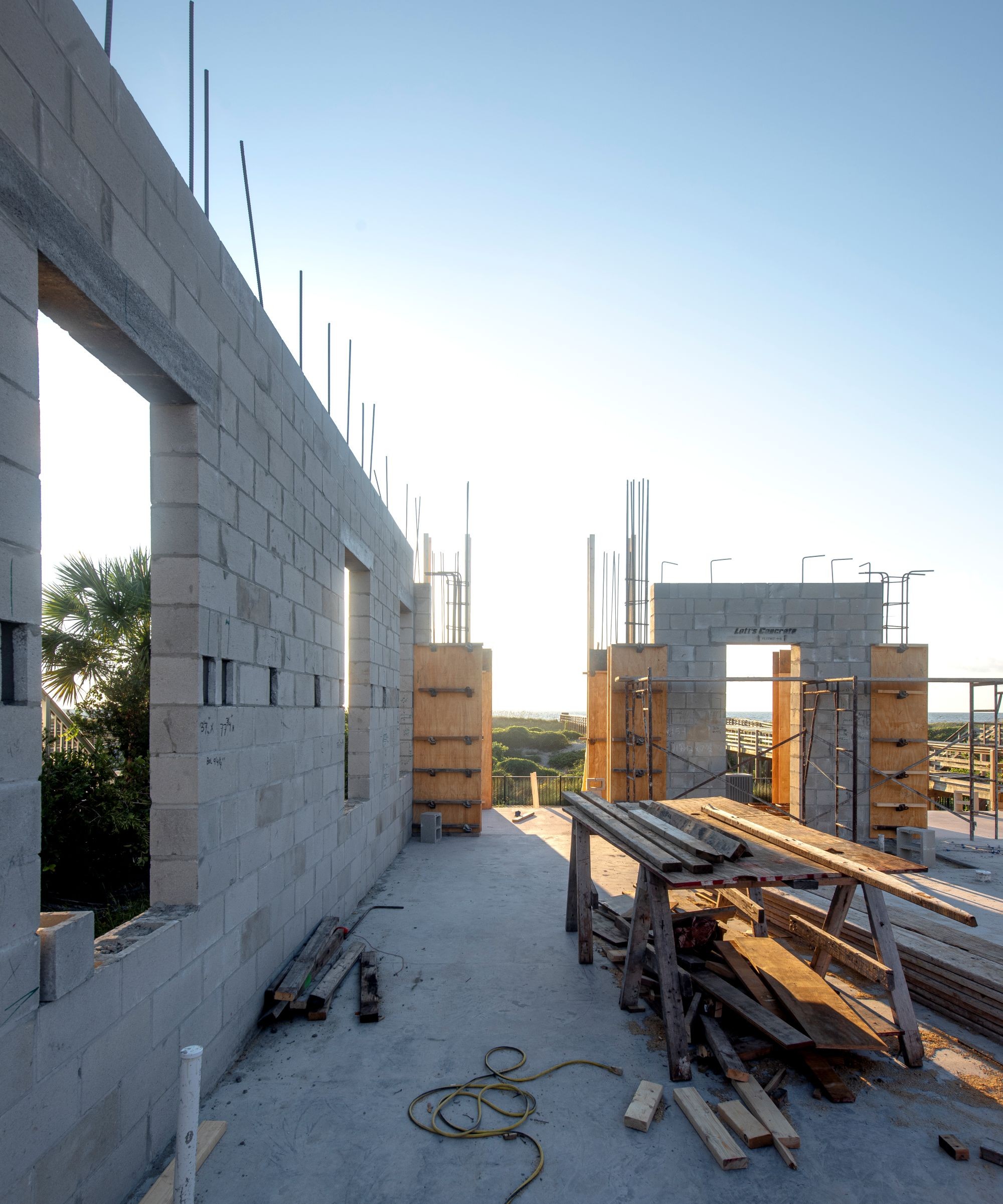 A partially built block wall with concrete floor and wood piled up