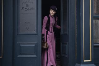 Miss Scarlet coming out of Nash & Sons in a pink and black dress.