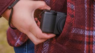 Ricoh GR IV HDF compact camera being taken out of a woman's coat pocket