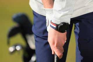 Golfbuddy watch on the wrist whilst player waits to hit shot