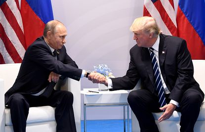 Vladimir Putin shakes hands with Donald Trump.
