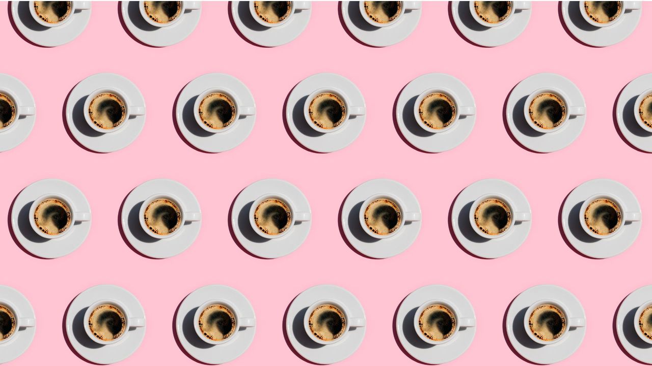 Pattern made of cup of fresh coffee on pastel pink color background. Directly above view of fresh coffee in white cups. 