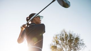 Woman swinging a golf club outdoors close-up