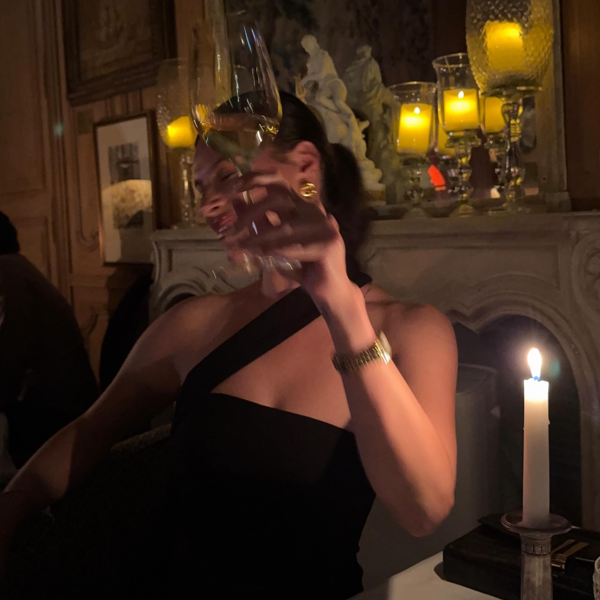Woman raising her wine glass at a dimly lit dinner table.