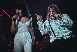 Meatloaf on stage performing with Karla Devito. They are shown in a 3/4-length view. He is pointing toward the audience. Photograph, 1978