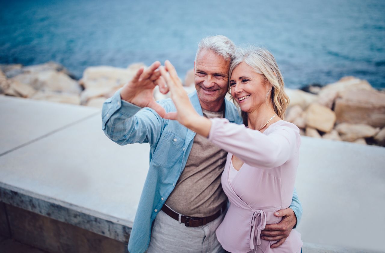 Mature couple making heart shape with their hands at seaside