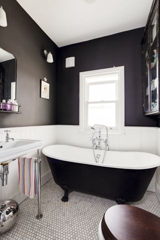 Bold bathroom with black freestanding bath, hexagonal floor tiles, basin and mirror