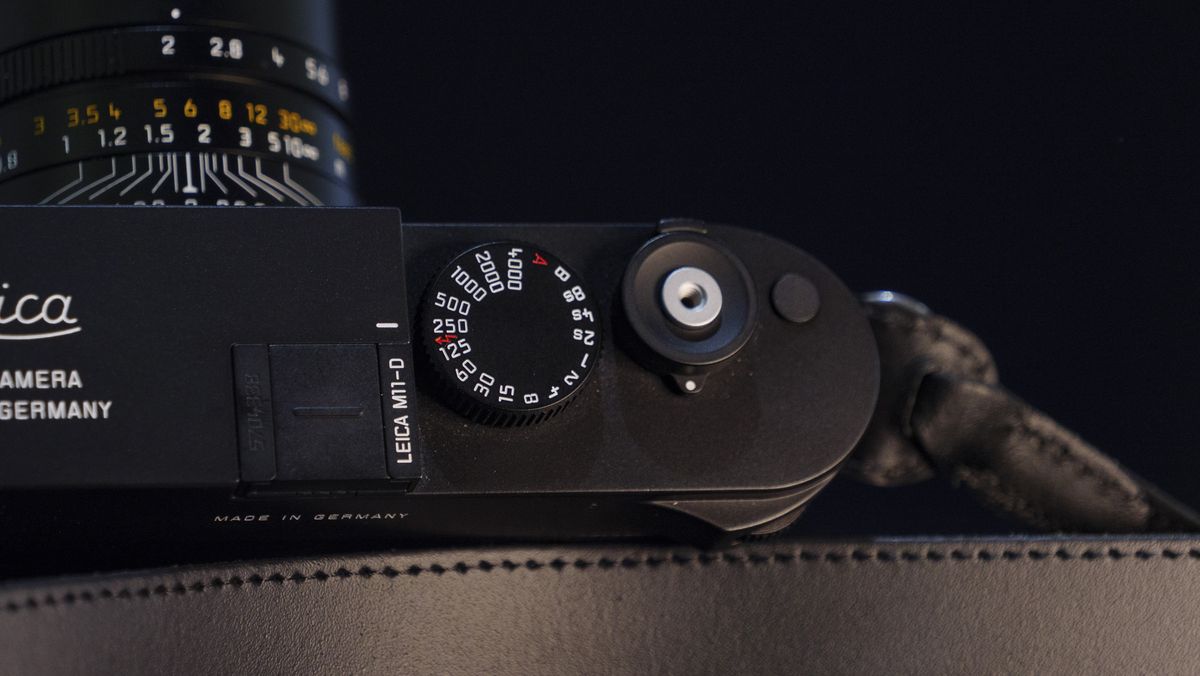 Leica M11-D camera on a dark blue table, low key lighting, closeup of shutter speed dial