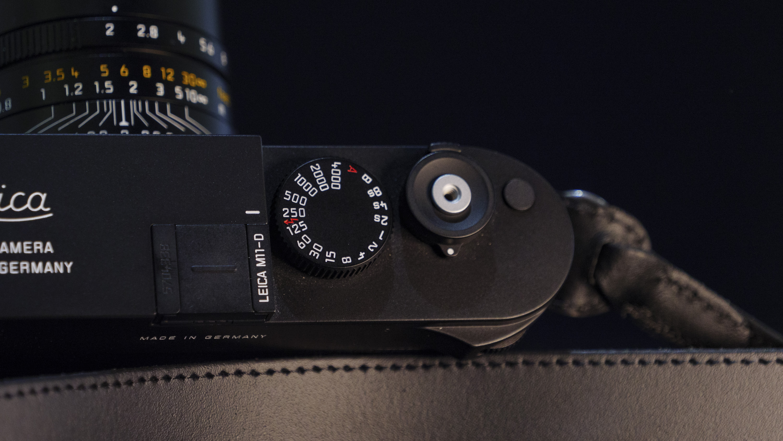 Leica M11-D camera on a dark blue table, low key lighting, closeup of shutter speed dial