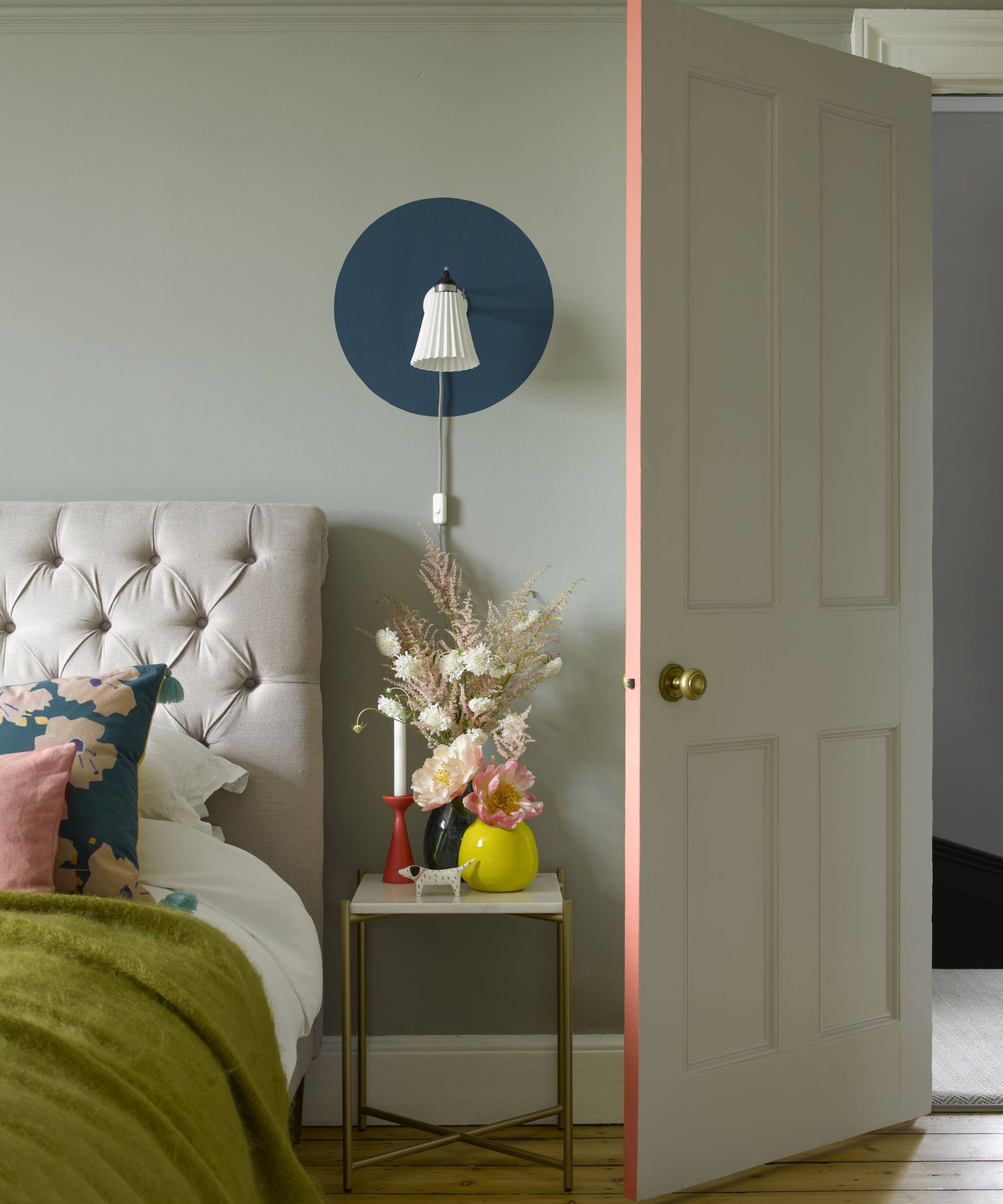 bedroom with edge of door painted pink and blue circle painted behind wall light