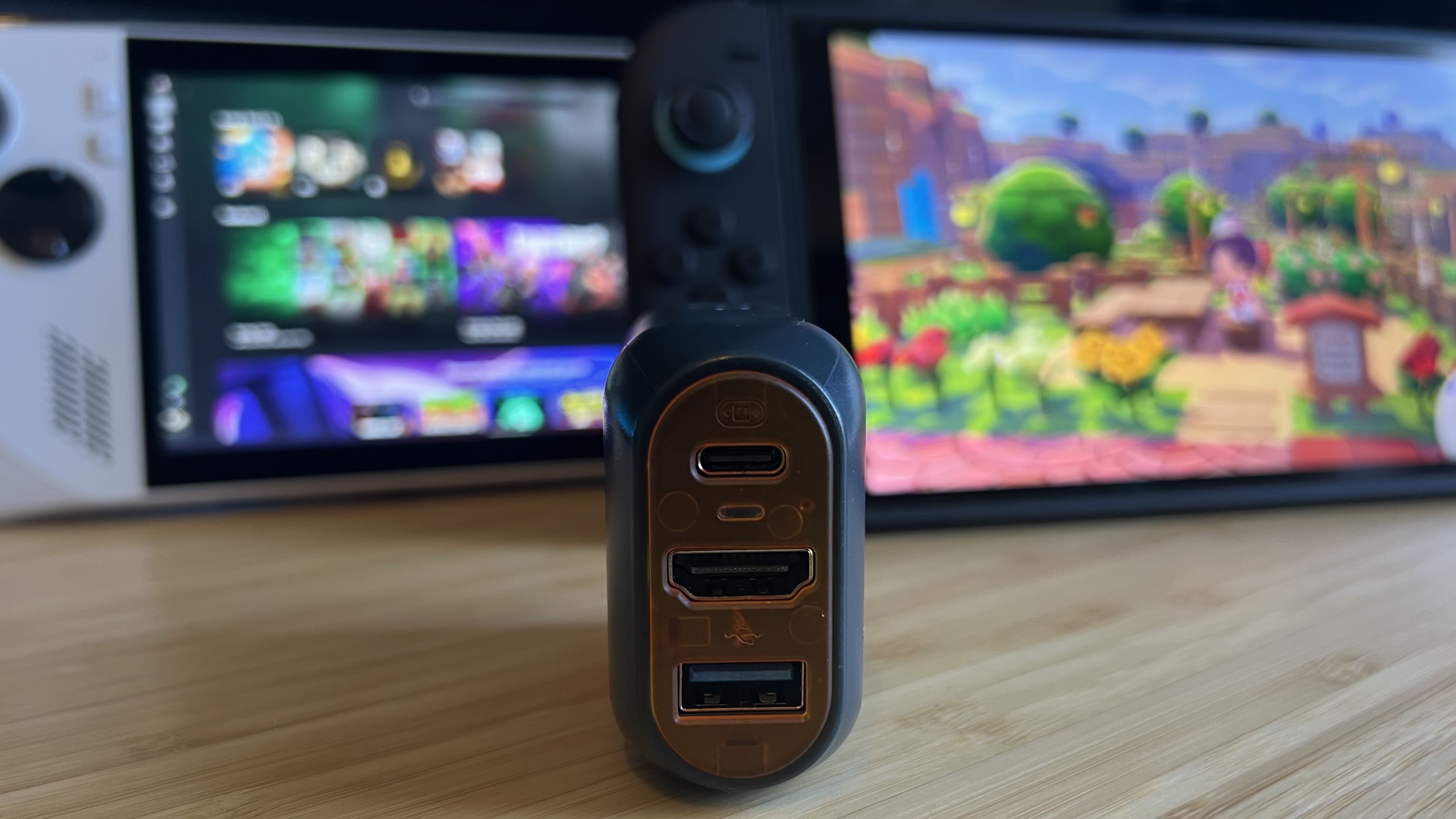 Genki Covert Dock 3 with ports facing the camera in front of an Asus ROG Ally and Nintendo Switch 2 on a wooden desk