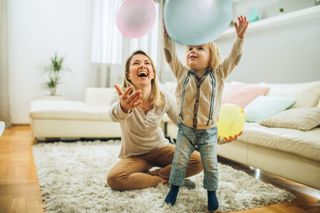 Happy mother and her small son playing with a balloons at home