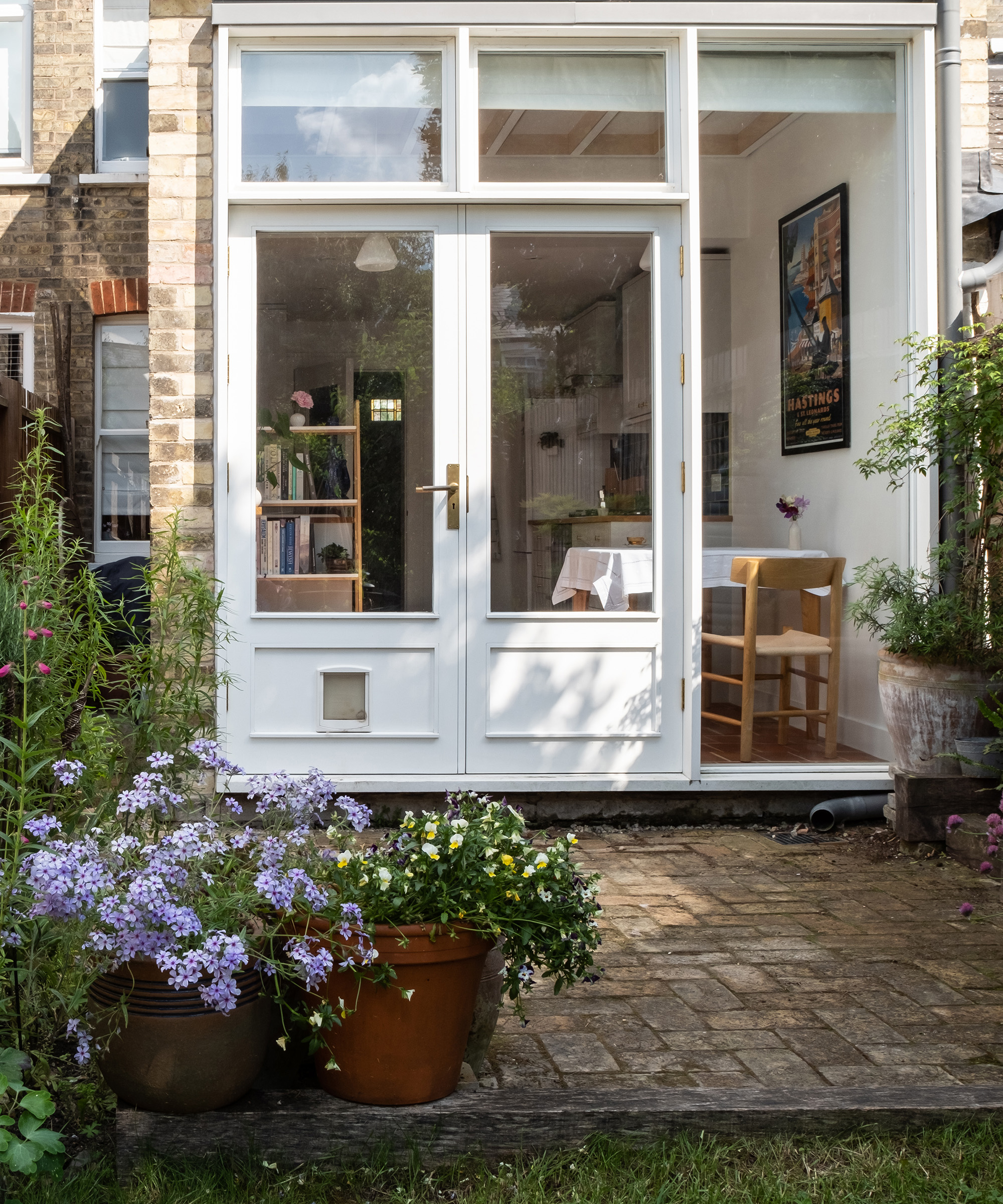 A brick patio area in front of patio french doors with pots of plants defining the area