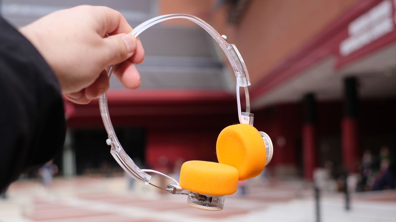 A photograph of the FiiO EH11 on-ear headphones with a transparent frame and orange foam earpads.