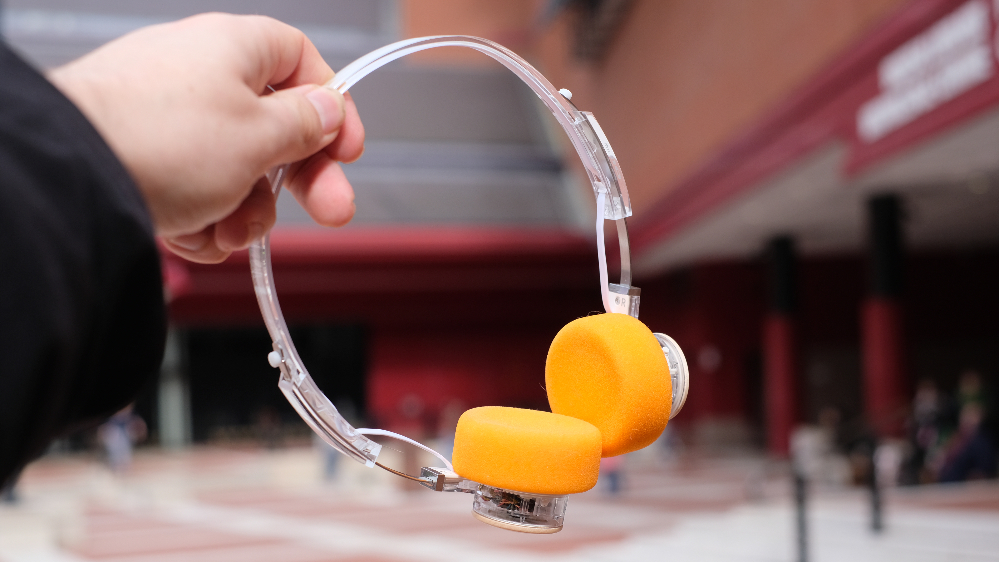 A photograph of the FiiO EH11 over-ear headphones with a transparent frame and orange foam earpads.