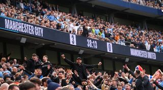 Manchester City fans celebrate as the scoreboard shows their team are 3-0 up against Manchester United in the derby at the Etihad Stadium.