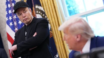 Elon Musk listens as Donald Trump speaks to reporters in the Oval Office in May