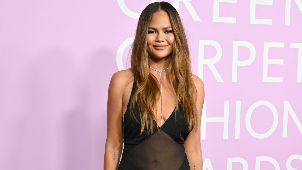 Chrissy Teigen wearing a black sheer saint laurent gown at the Green Carpet Fashion Awards