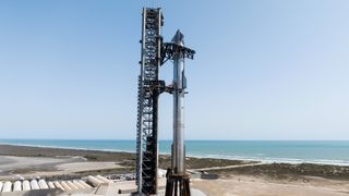 A giant SpaceX Starship rocket on the launch pad with the ocean in the background