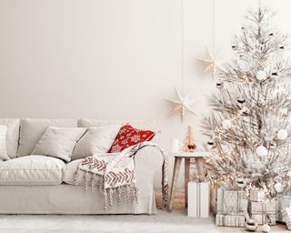 netural christmas decor in an off-white living room with off-white tree and a red blanket thrown in