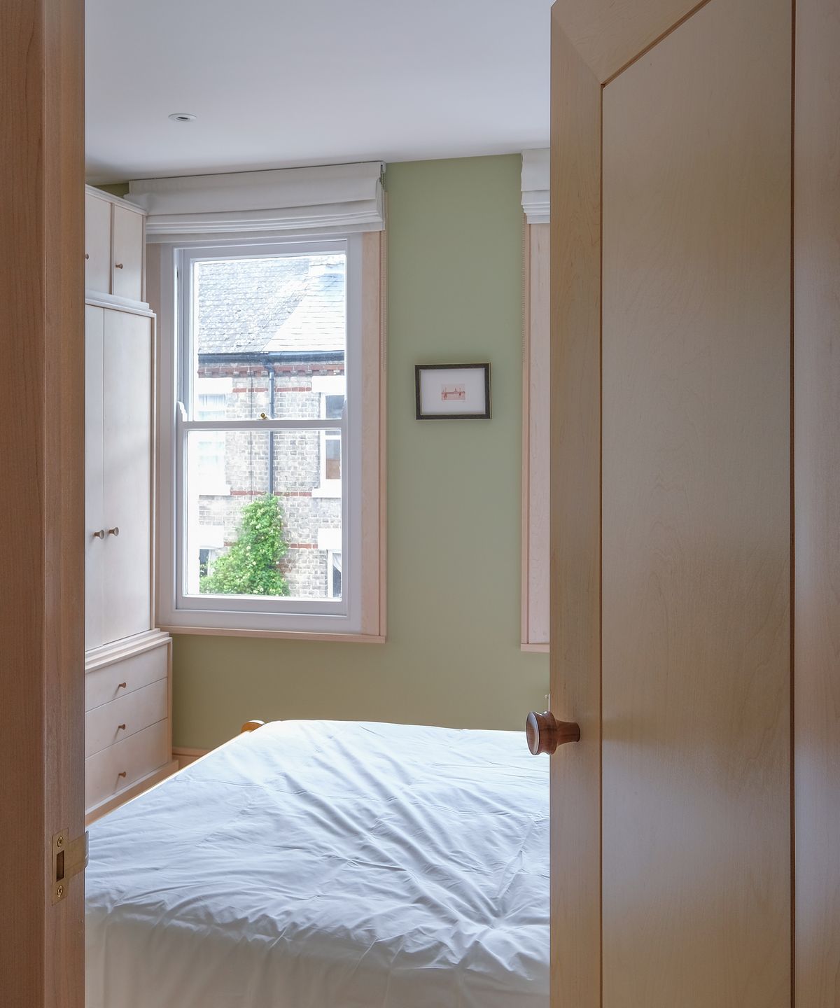 Birch plywood storage and internal door looking into a small double bedroom