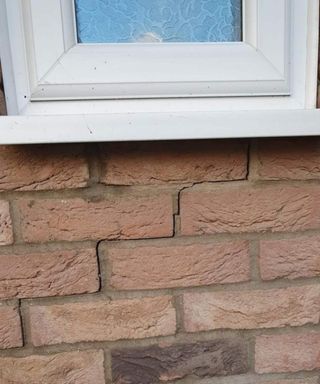 A close up image of a cracked wall below a window