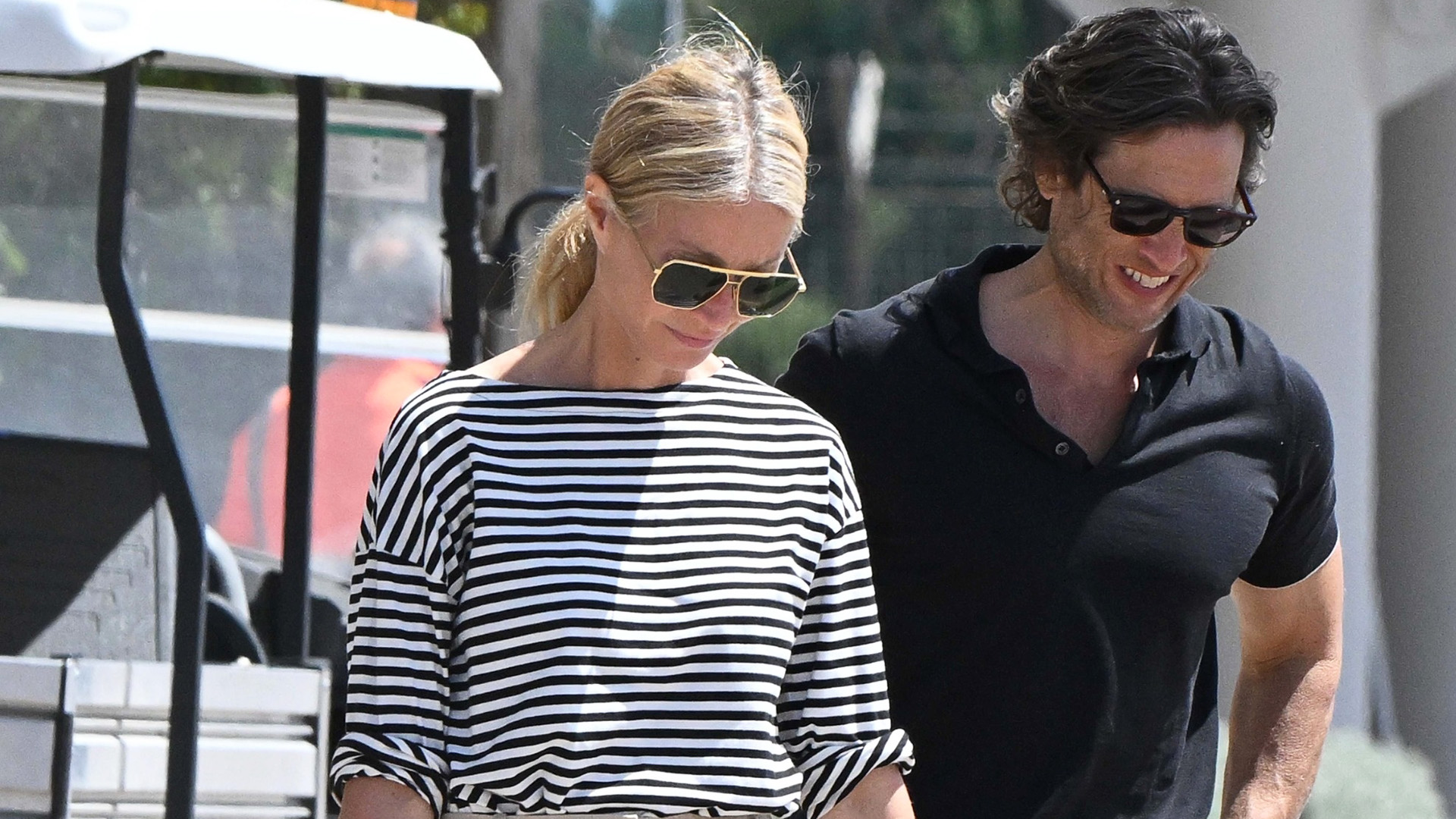 Gwyneth Paltrow wearing a striped tee with khaki pants, a Goyard tote, and ankle-wrap sandals in Sardinia