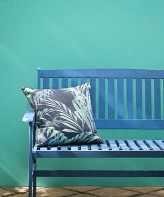 Bench painted a deep blue in front of an aqua blue wall